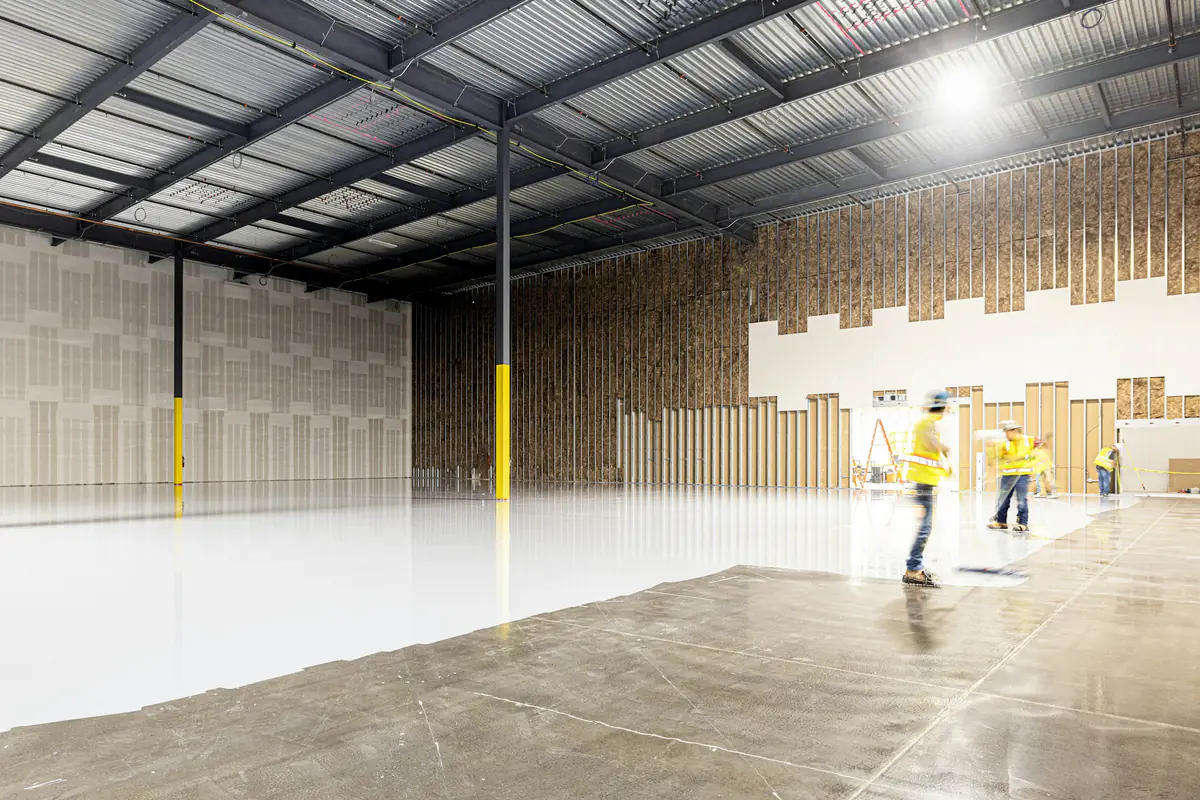 Two workers preparing a large interior floor slab